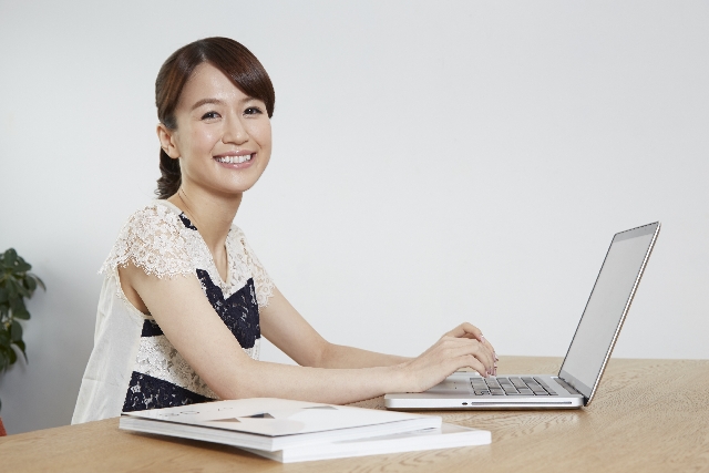 パソコンで翻訳の仕事をする笑顔の女性