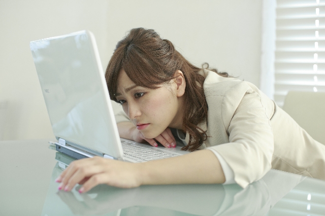 ノートパソコンを使う疲れた女性